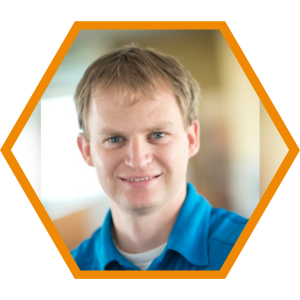 Headshot of Associate Principal Adam Bunnell in an orange hexagon frame.