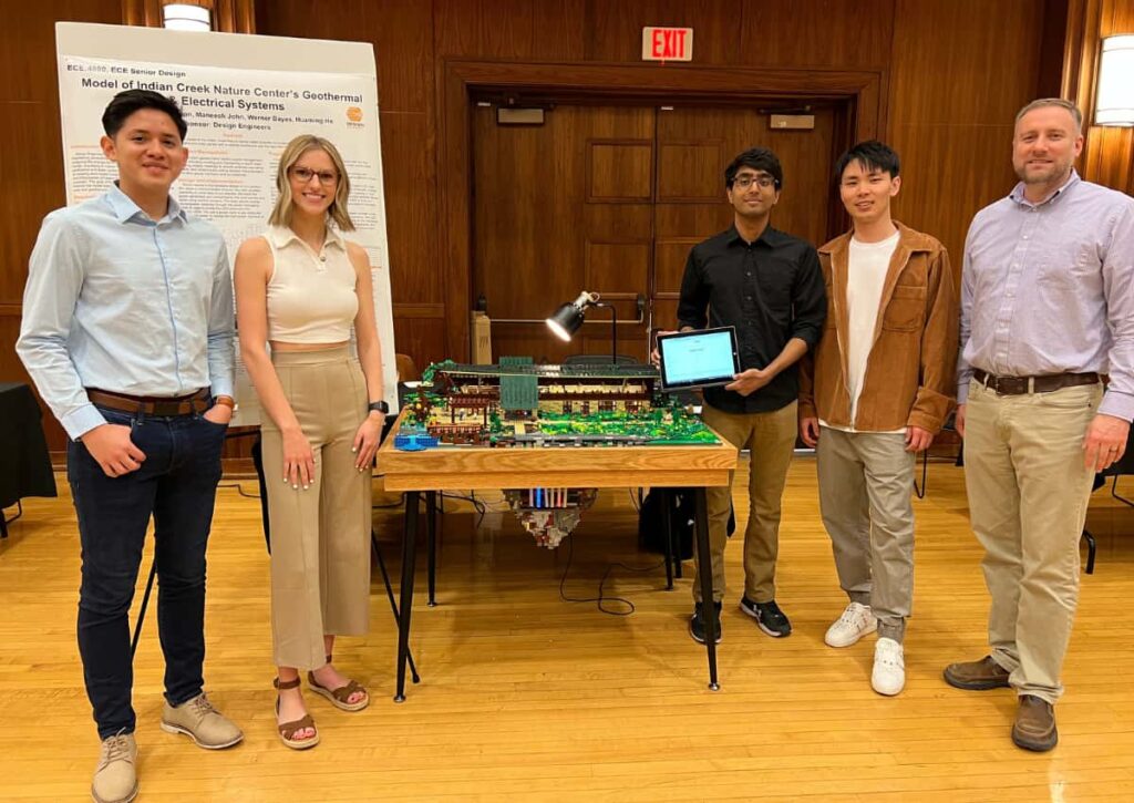 University of Iowa students Maneesh John, Werner Bayas, Haming He, and Kiana Erikson with Design Engineers' Principal Jonathan Gettler with the upgraded lego model at the Senior Design exhibit.