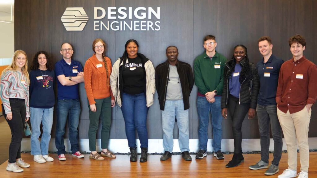 Students from the Engineers Without Borders Chapter at Iowa State University, Kwame Nkrumah University of Science and Technology, and employees standing in front of the Design Engineers sign.
