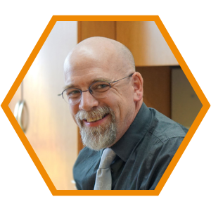Headshot of Managing Principal Dwight Schumm in an orange hexagon frame.