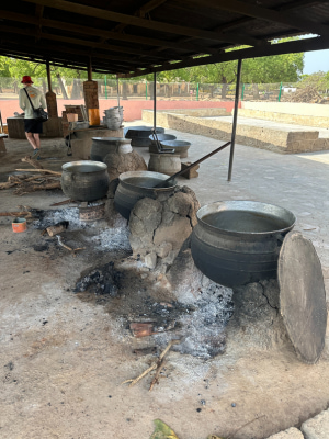 Multiple pots under a covered shelter at Ullo High School kitchen.